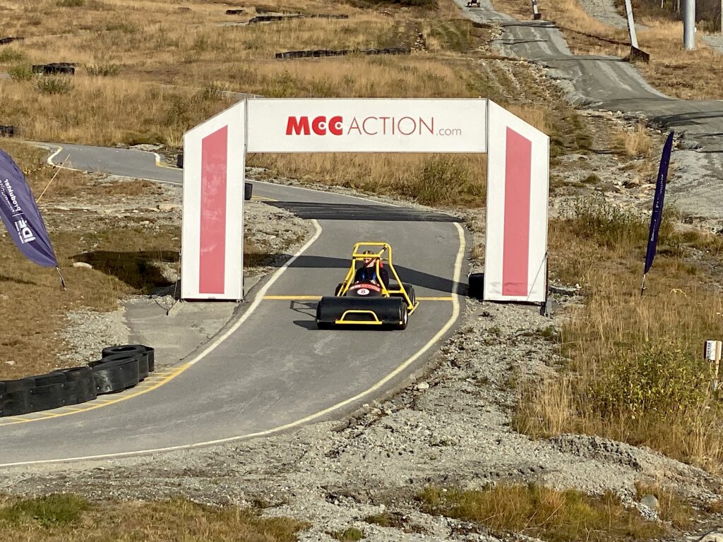 Målet til olabilbanen i bunnen av alpinbakken på Beitostølen. En olabil med en mann inni er på vei over målstreken.