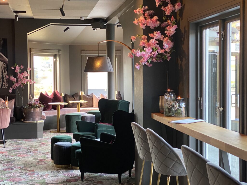 Utsnitt fra en moderne restaurant på Beitostølen, med stoler, puter og en sofa i myk velur. Rosa blomster på veggen.